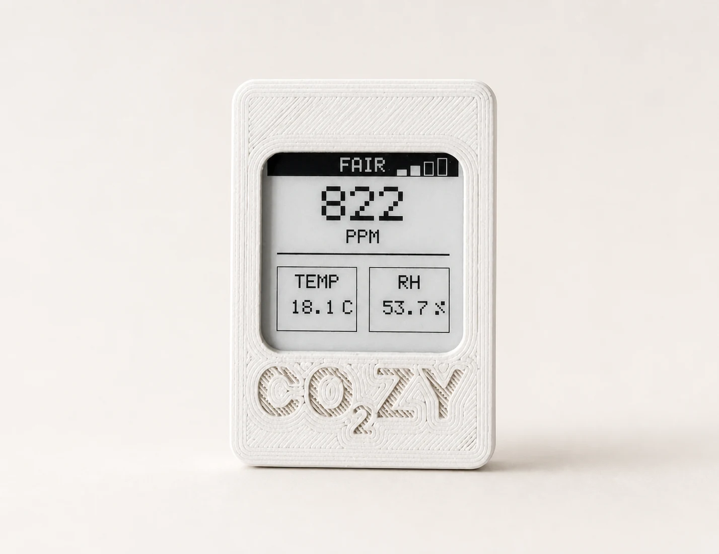 White 3D-printed CO₂ZY portable CO2 monitor in a warm studio setting