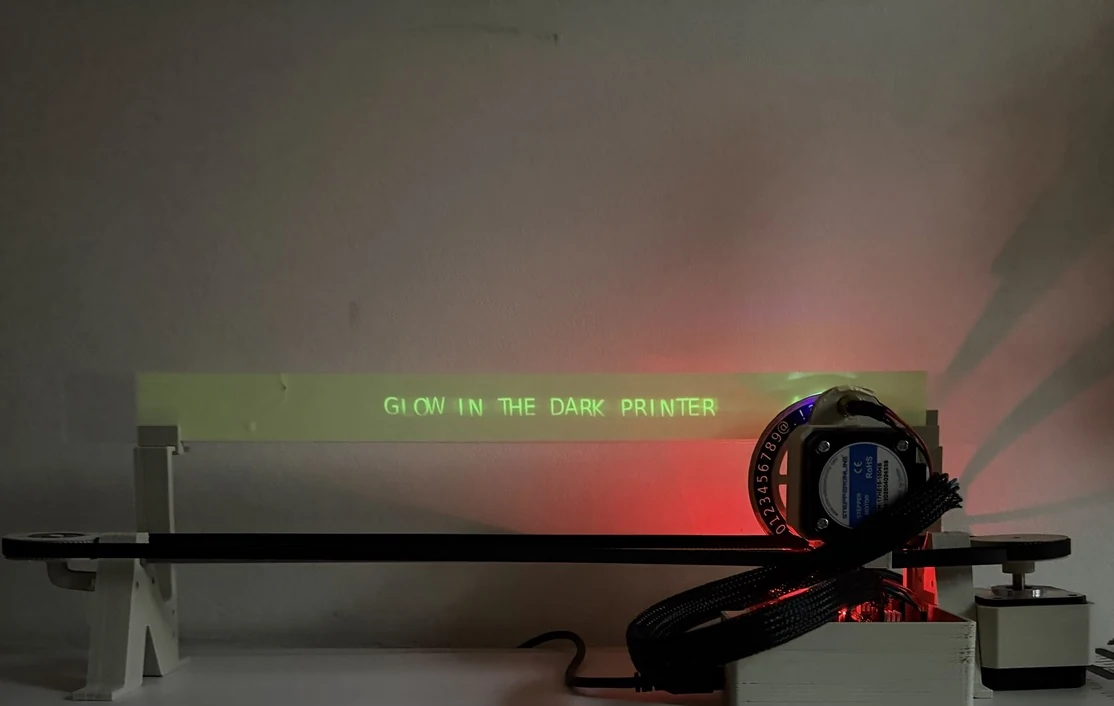 Glow printer writing luminous green text in a dim room